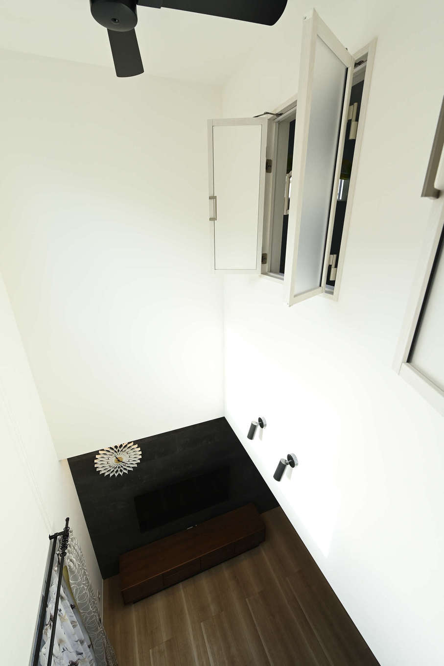 トーリンホーム【デザイン住宅、子育て、間取り】2階の子ども部屋の室内窓から眺めたリビング。2室の子ども部屋のそれぞれに白い室内窓が設けてあり、常に家族の気配を感じとれる。隣室の姉妹や階下の家族と部屋にいながら声を掛け合うこともできるそう