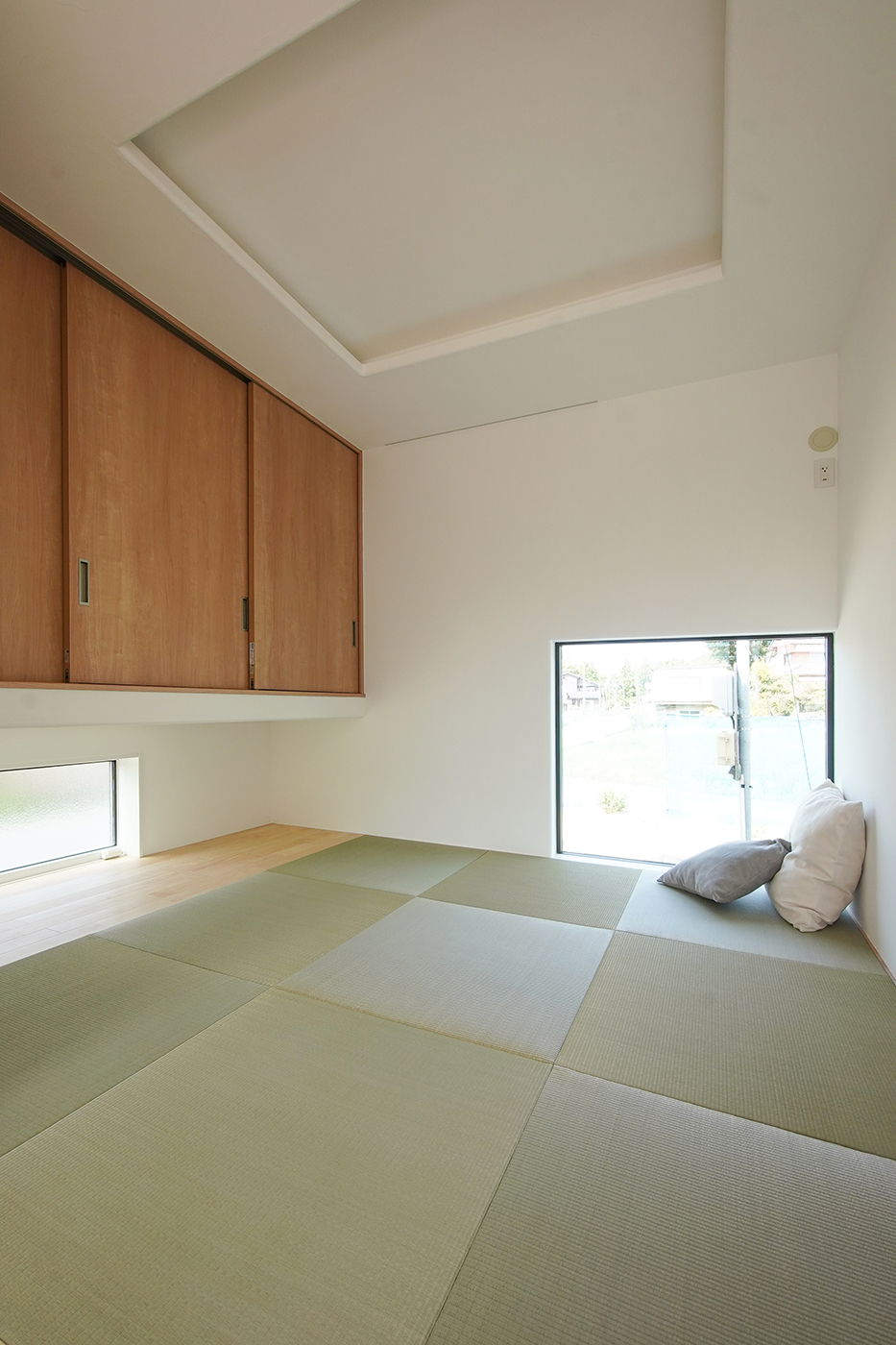 花みずき工房【自然素材、間取り、ガレージ】折り上げ天井にやわらかな間接照明を取り入れた和室は、4.5帖。小上がりスペースでリビングと緩やかに繋がる。地窓を2つ設けているので、北西に位置するこの場所も明るく気持ちがいい