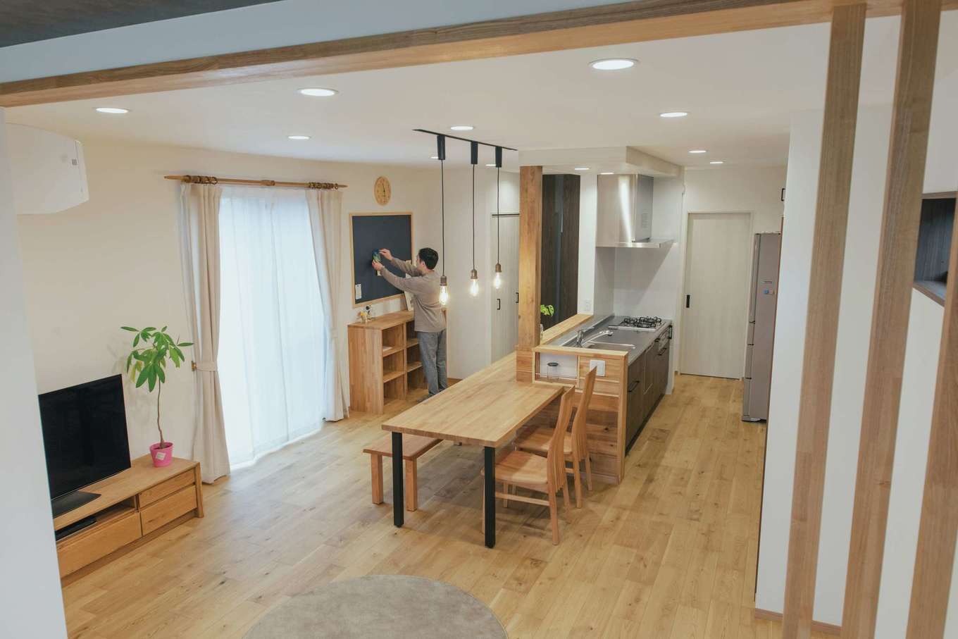 ほっと住まいる【デザイン住宅、自然素材、狭小住宅】キッチンを囲むカウンターテーブルは同社からの贈り物。正面には子どもの学校道具をしまう造作収納と黒板ボードも設けた