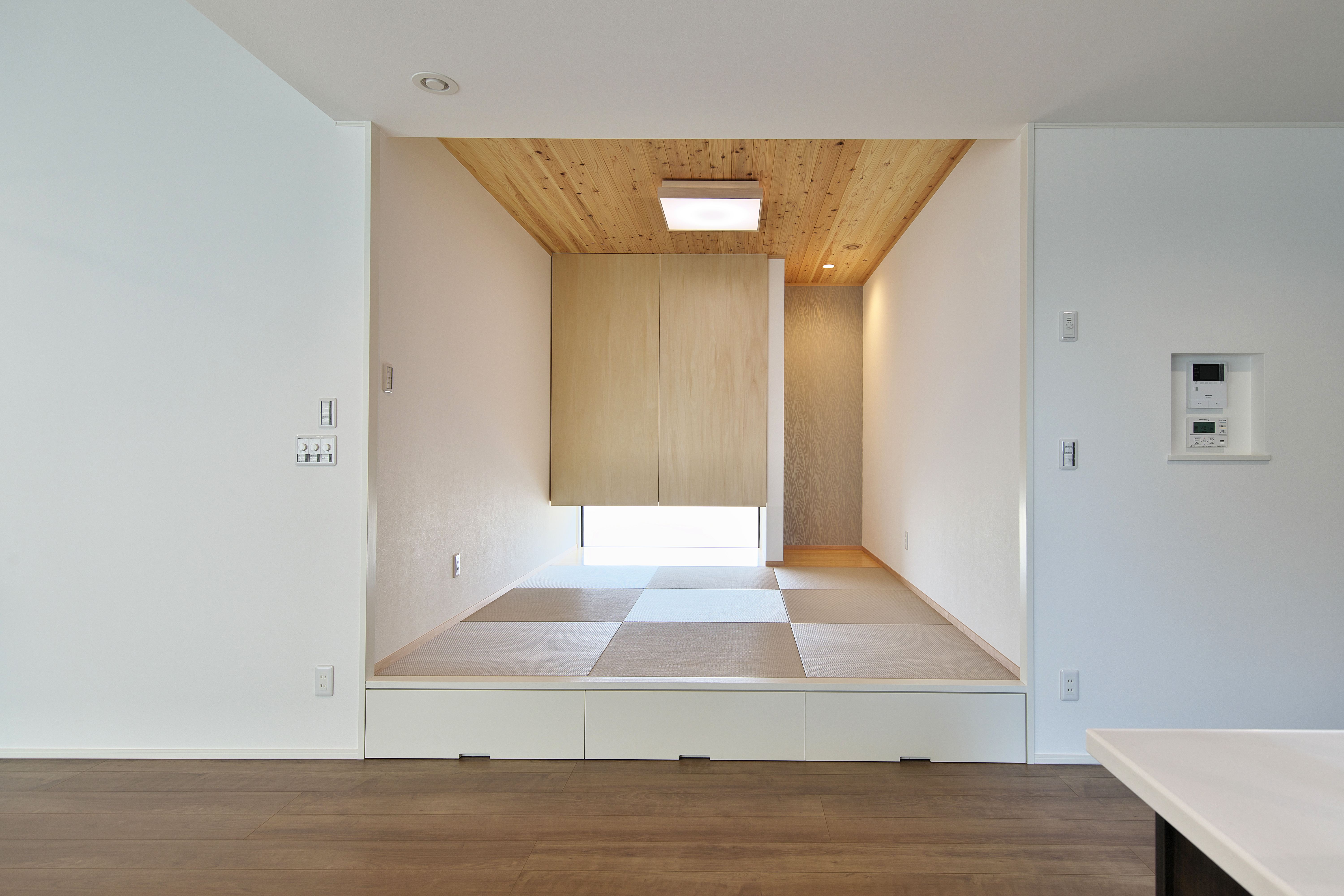 タムラホーム｜モダンな小上がりの畳スペース。シンプルなデザインで部屋全体と調和しており、くつろぎの空間を提供する。天井の木目が温かみを感じさせる。