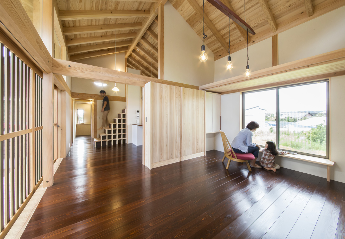 石牧建築【収納力、自然素材、建築家】垂木、Jパネルが現しとなり、天竜杉の香りが心地いいLDK。緑豊かな田んぼの景色を楽しむために、北面にも大きな開口部を設置した。艶やかに輝く無垢の床は、建築家と『石牧建築』のスタッフ、施主さん家族が一緒にワークショップで漆塗装を施した