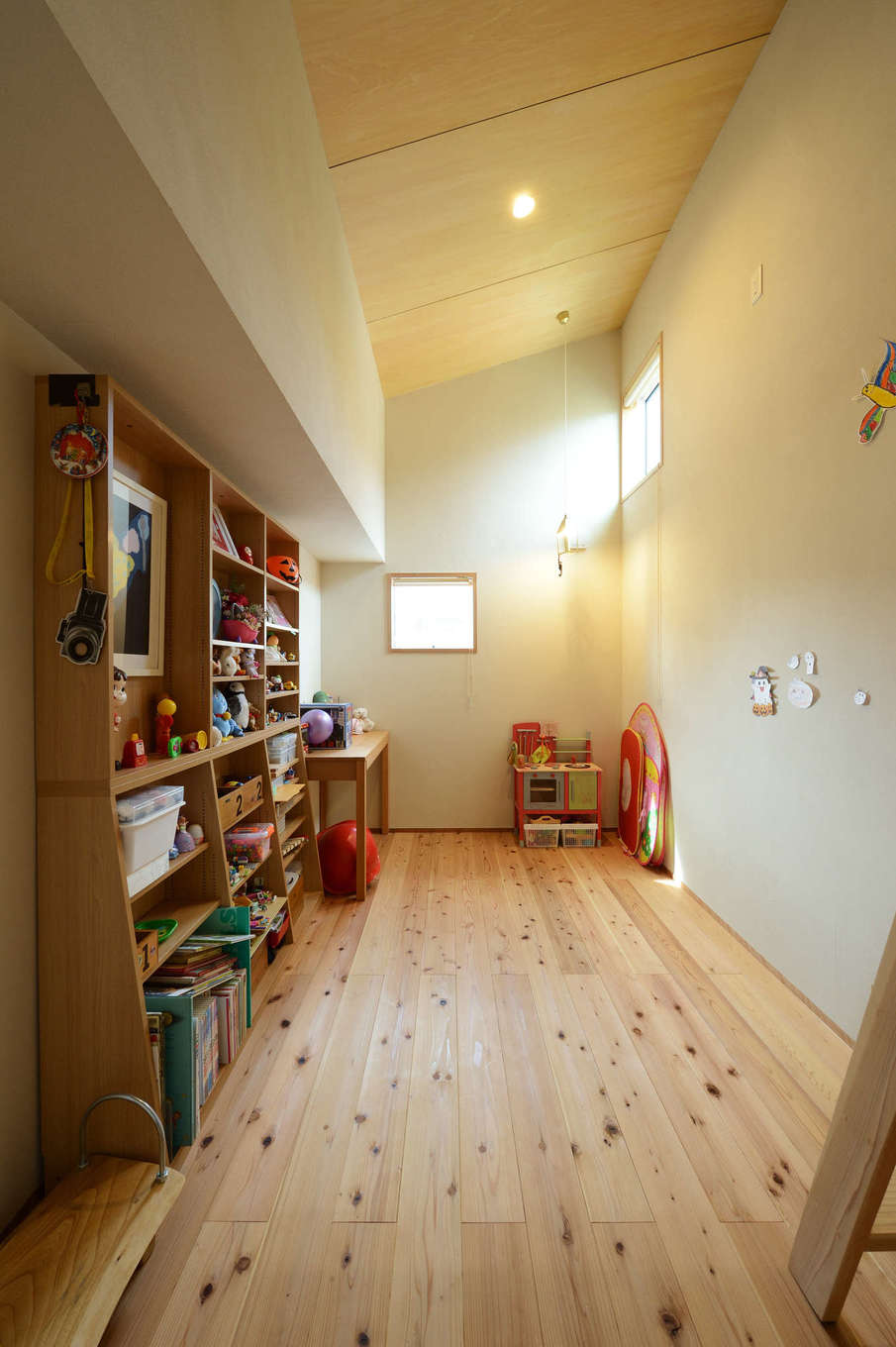 石牧建築【自然素材、狭小住宅、建築家】天井の低い2階の廊下から一歩中に入ると、高い天井が広がる長女の部屋。調湿効果にすぐれた、あたたかい肌触りの無垢の木の家で過ごす子どもは、おだやかな性格の良い子に育ちそう