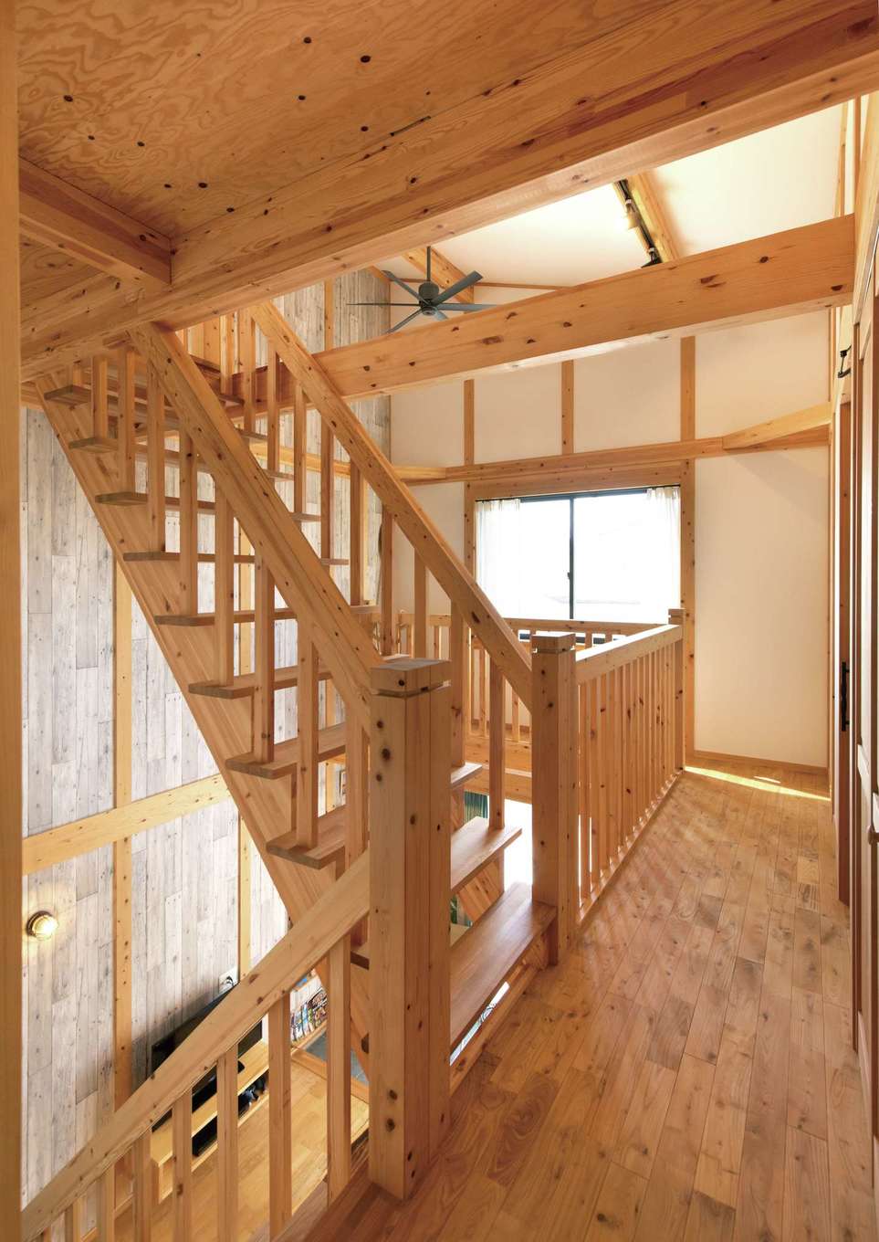 サイエンスホーム【子育て、趣味、自然素材】吹き抜けを通じて家族の声と気配が行き来する。階段や手すりにも無垢が使われる