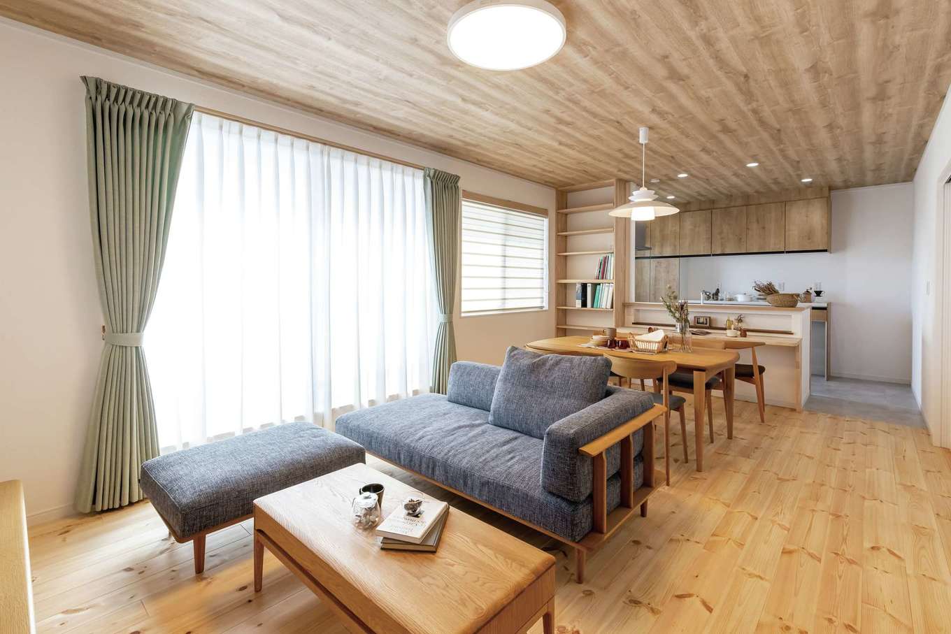 住まいるコーポレーション【二世帯住宅、自然素材、間取り】床に厚さ30mmの松の天然木、壁に珪藻土を用いた2階の子世帯のLDK。掃出窓の外には広いバルコニーを用意。2階なので周囲の視線も気にならず、窓を開けてのびのび過ごせる。広さは17.9畳、天井高は2.5mあるため、開放感も抜群だ
