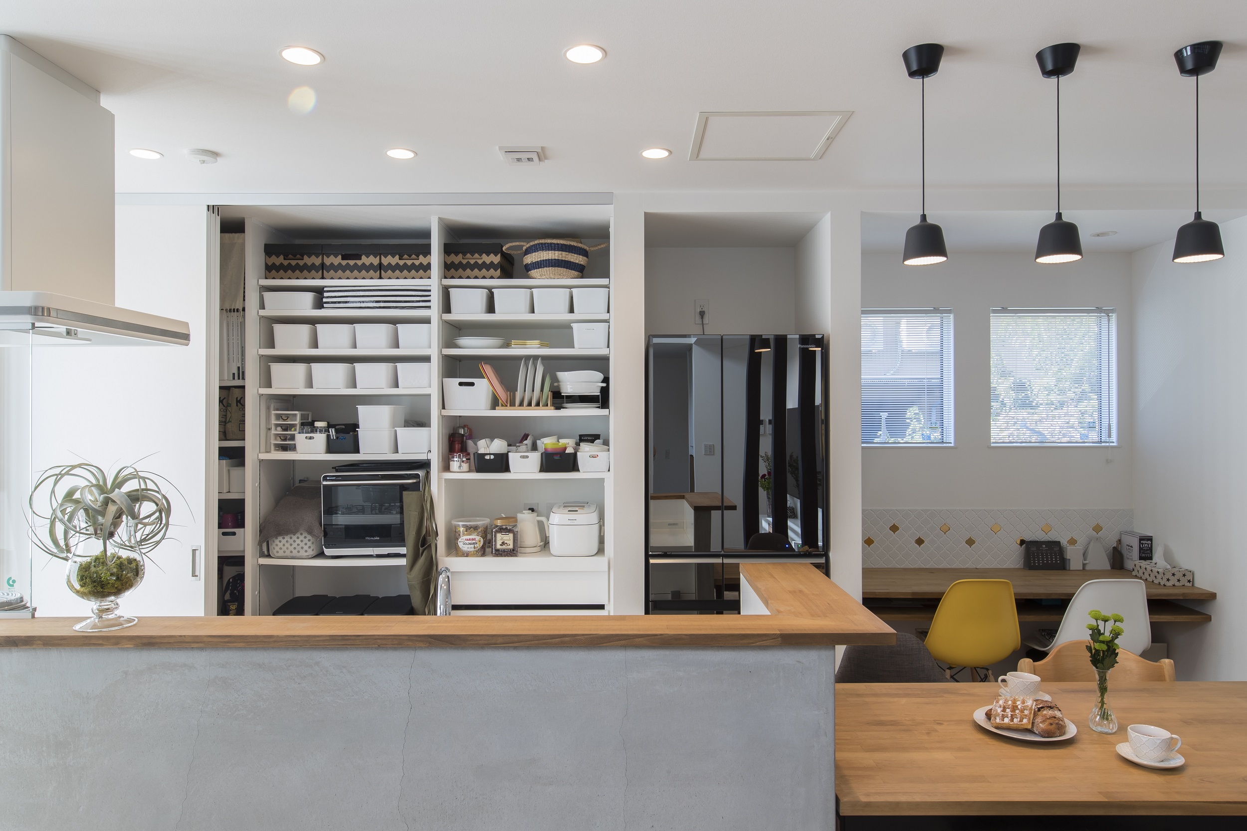 S.CONNECT（エスコネクト）【デザイン住宅、子育て、建築家】キッチンの背面の壁面収納は、引き戸を閉めて生活感を隠せば常に室内がすっきり・キレイ。壁のタイルや腰壁のモルタルなど、素材選びにもこだわった。ダイニング奥のスタディコーナーでは、子どもたちがママのすぐそばで勉強できる