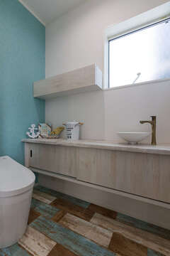 手洗いボウルや水栓金具にまでこだわったトイレ。マリン風に水色のアクセントクロスをセレクト