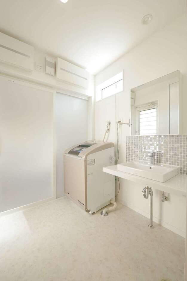 洗面台の下に収納棚を付けないことで開放感が生まれた。ワイドな鏡とタイルがアクセントに