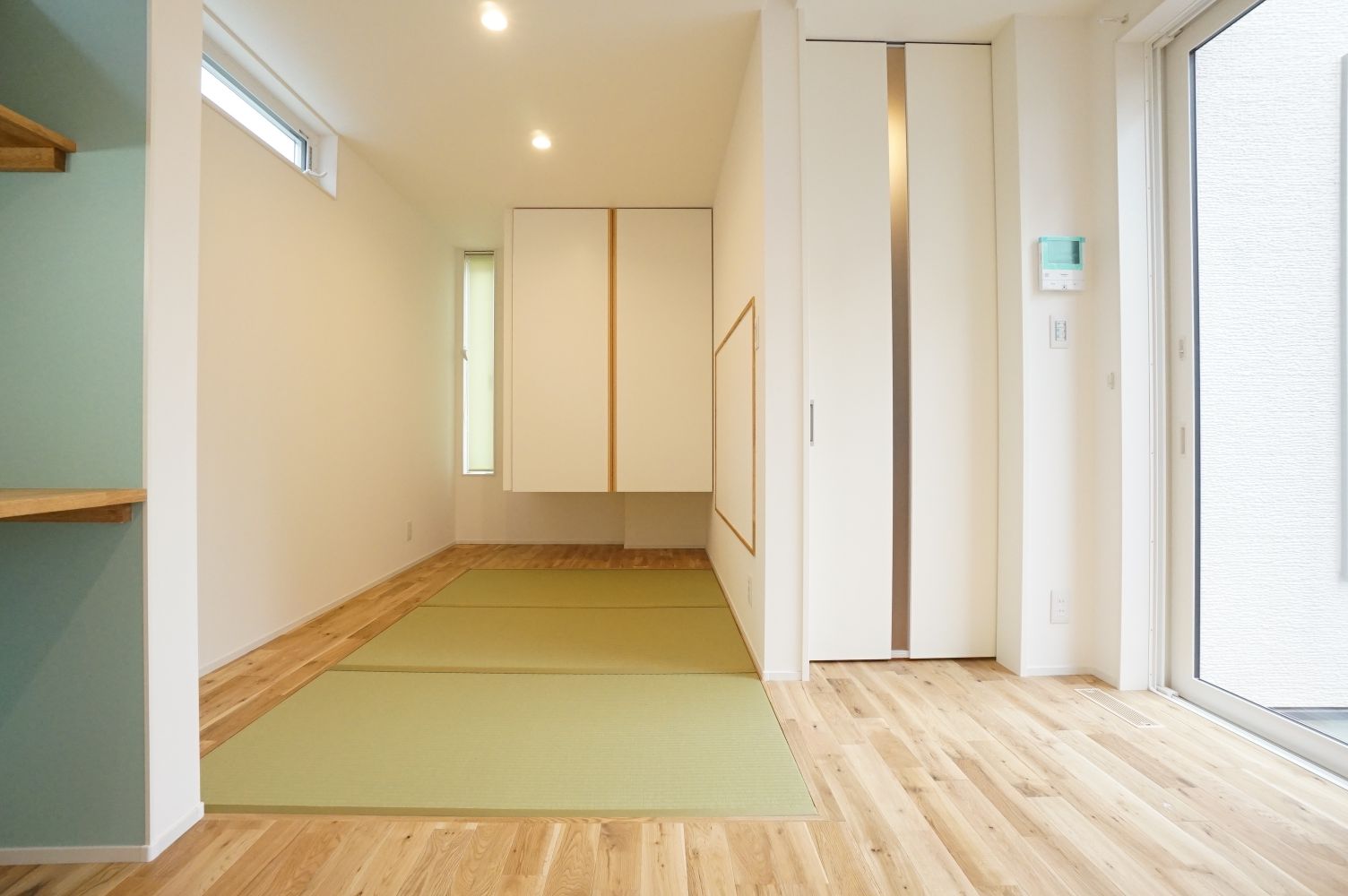RIKYU 一級建築士事務所【デザイン住宅、間取り、建築家】玄関から近い場所にある畳コーナー。天井まで届くリビングドアや吊押入れを採用したことで目線が上がり、空間がより広く感じられる