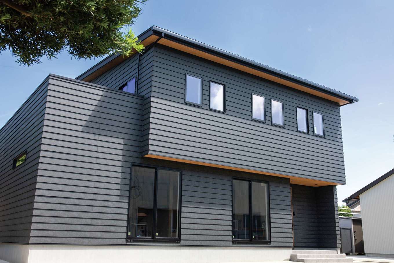 KUREKEN HAUS（榑林建設）【デザイン住宅、趣味、間取り】黒と木目調の軒天井を組み合わせた外観は当初からの希望。海が近いエリアなので、外壁は腐食に強く劣化しにくい素材を用いて、ランニングコストを削減