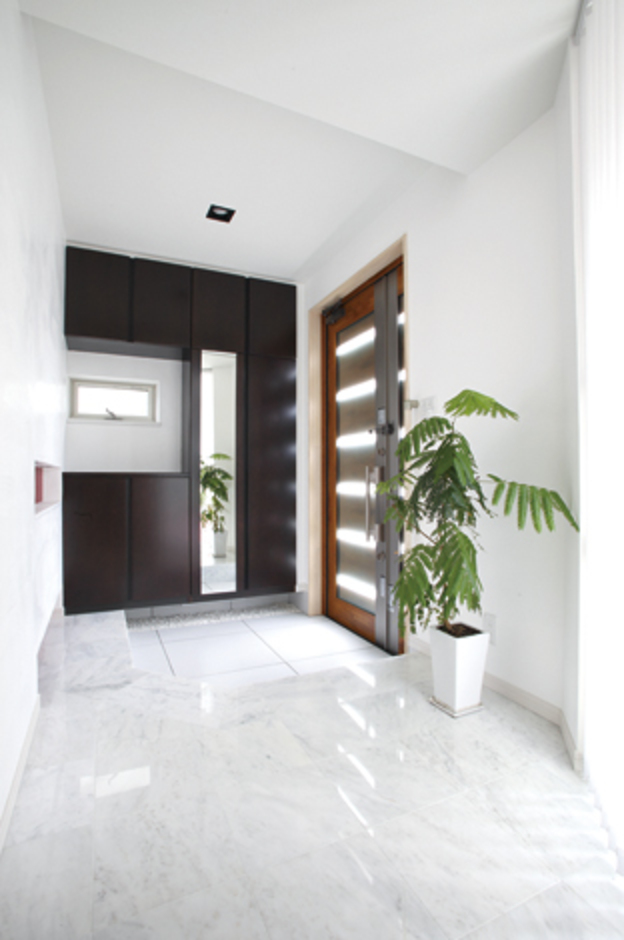 大理石張りの上質な玄関ホール。外からのアプローチに使用したレザー調の600角タイルは納得オリジナル