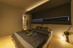 夫妻の寝室は間接照明などを用いてホテルライクな雰囲気を重視。ベッドヘッドは壁をふかして携帯電話などが置けるようにしている