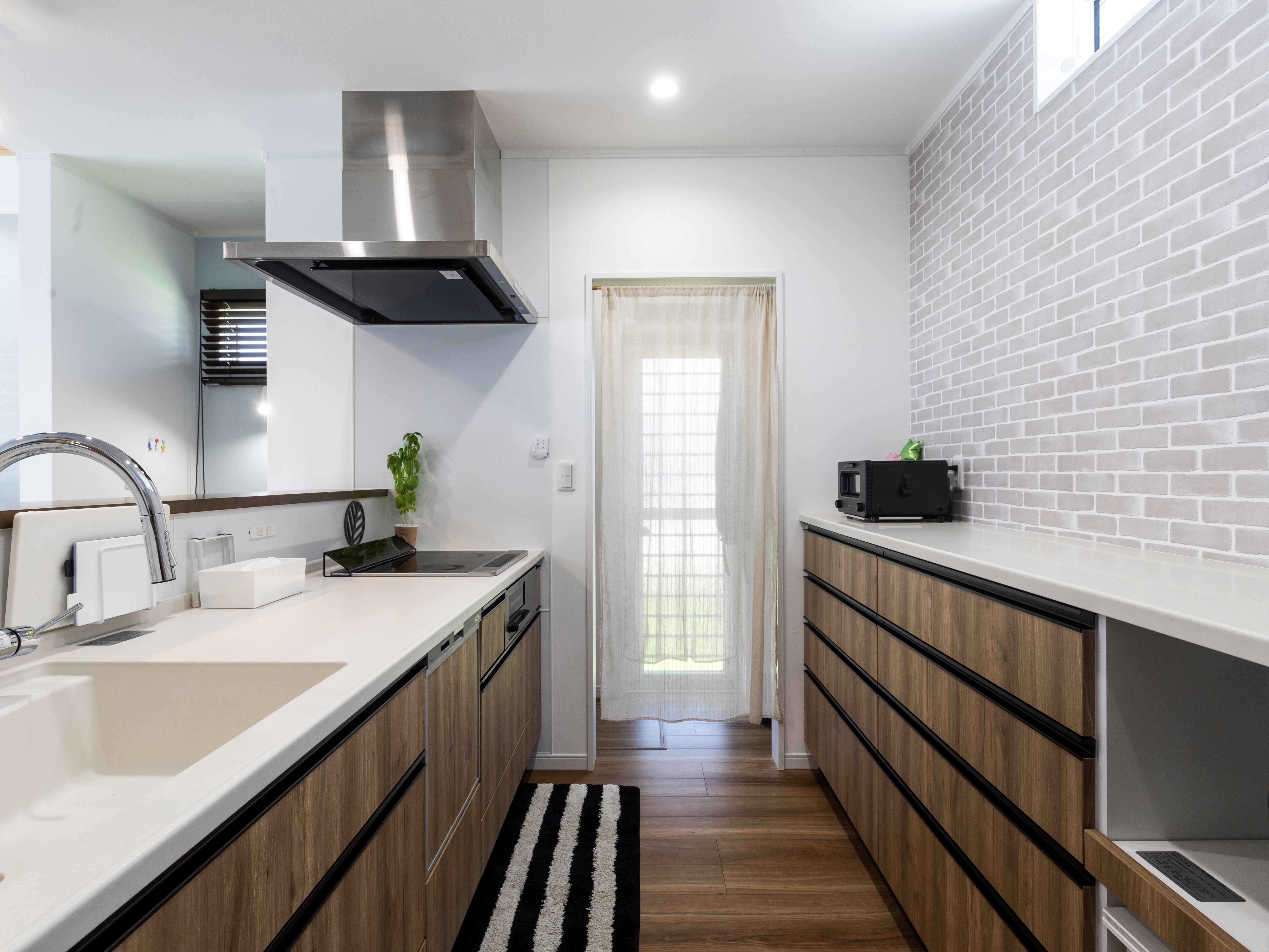 エスホーム｜シンプルで機能的なキッチン空間。白を基調とした清潔感あるデザインで、広々とした作業スペースが魅力。モダンな壁面のタイルがアクセントで、快適に調理ができる。