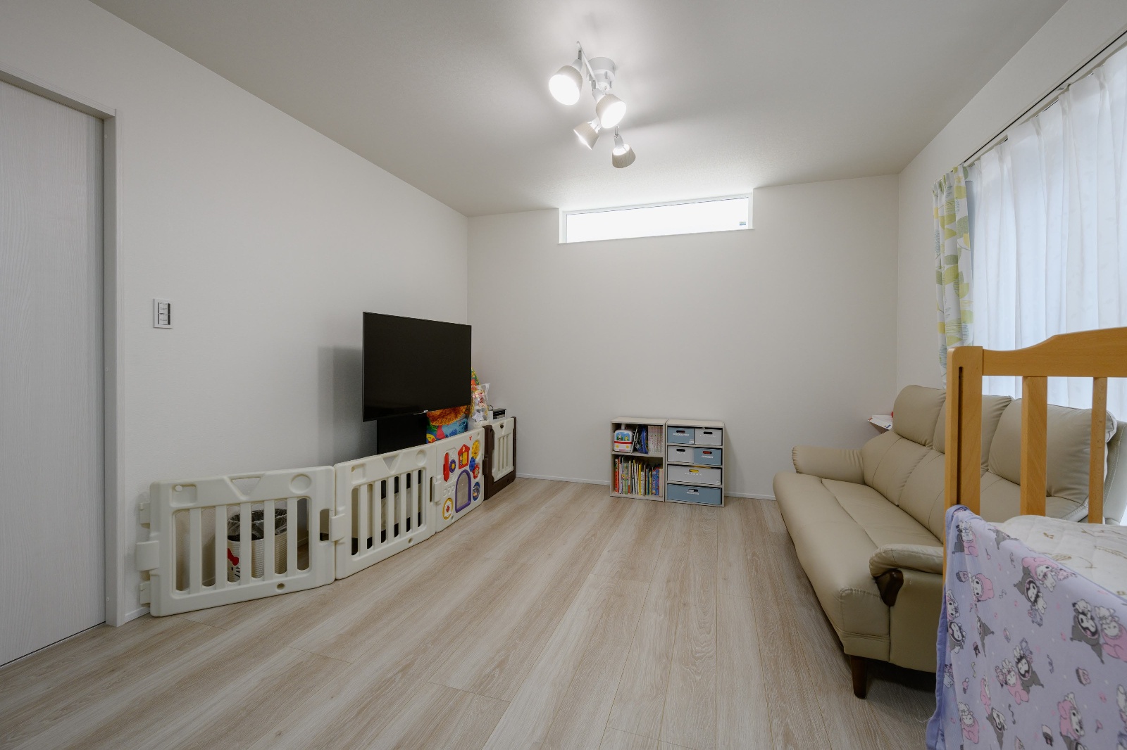 K-rise｜白を基調とした明るい子ども部屋。おもちゃや家具が整然と配置され、床には保護フェンスが設置されているため、安全で安心できる空間になっている。
