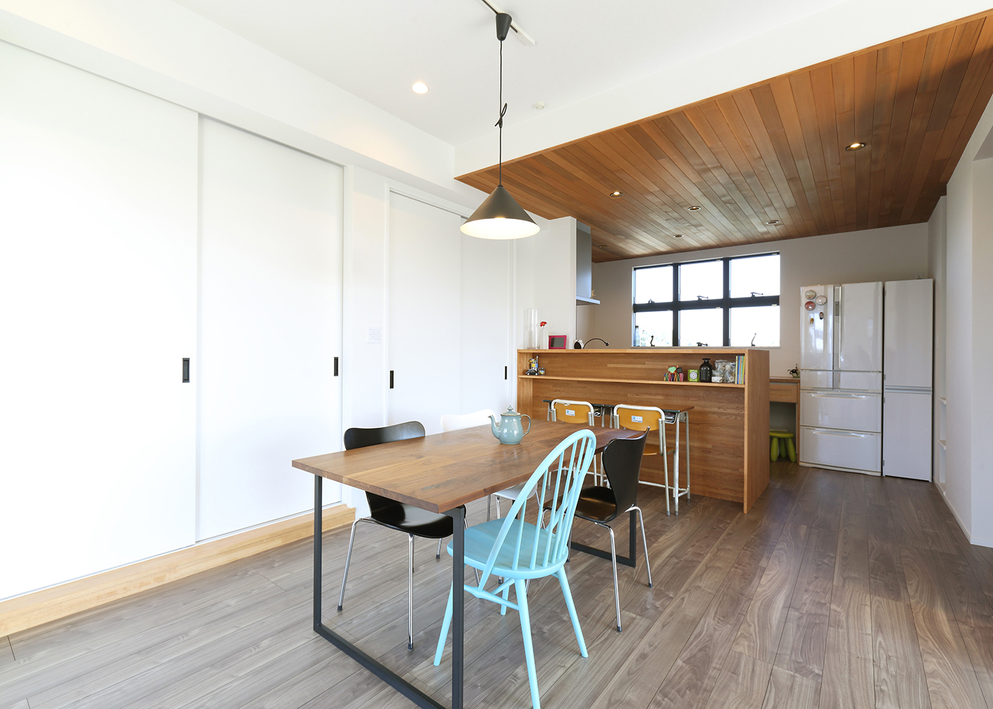 丸昇彦坂建設【デザイン住宅、趣味、インテリア】キッチンの下がり天井でLDKにアクセントが付き、一つの空間としても、別々の空間としても魅力を引き立ててくれる。ダイニングテーブルを照らすペンダントライトは、優しい光で食卓を包んでくれる