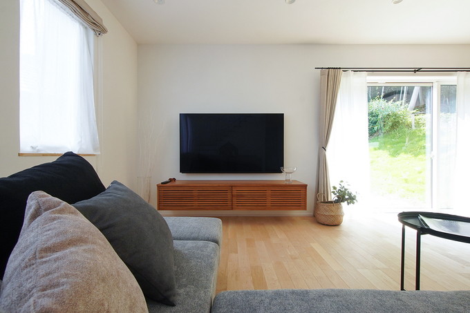 裏山の緑を借景に望むリビング。壁掛けテレビ下のテレビボードも造作で、足元を浮かせるデザインに仕上げてもらった。スタイリッシュなだけでなく掃除もしやすい、機能性を考えた設計だ