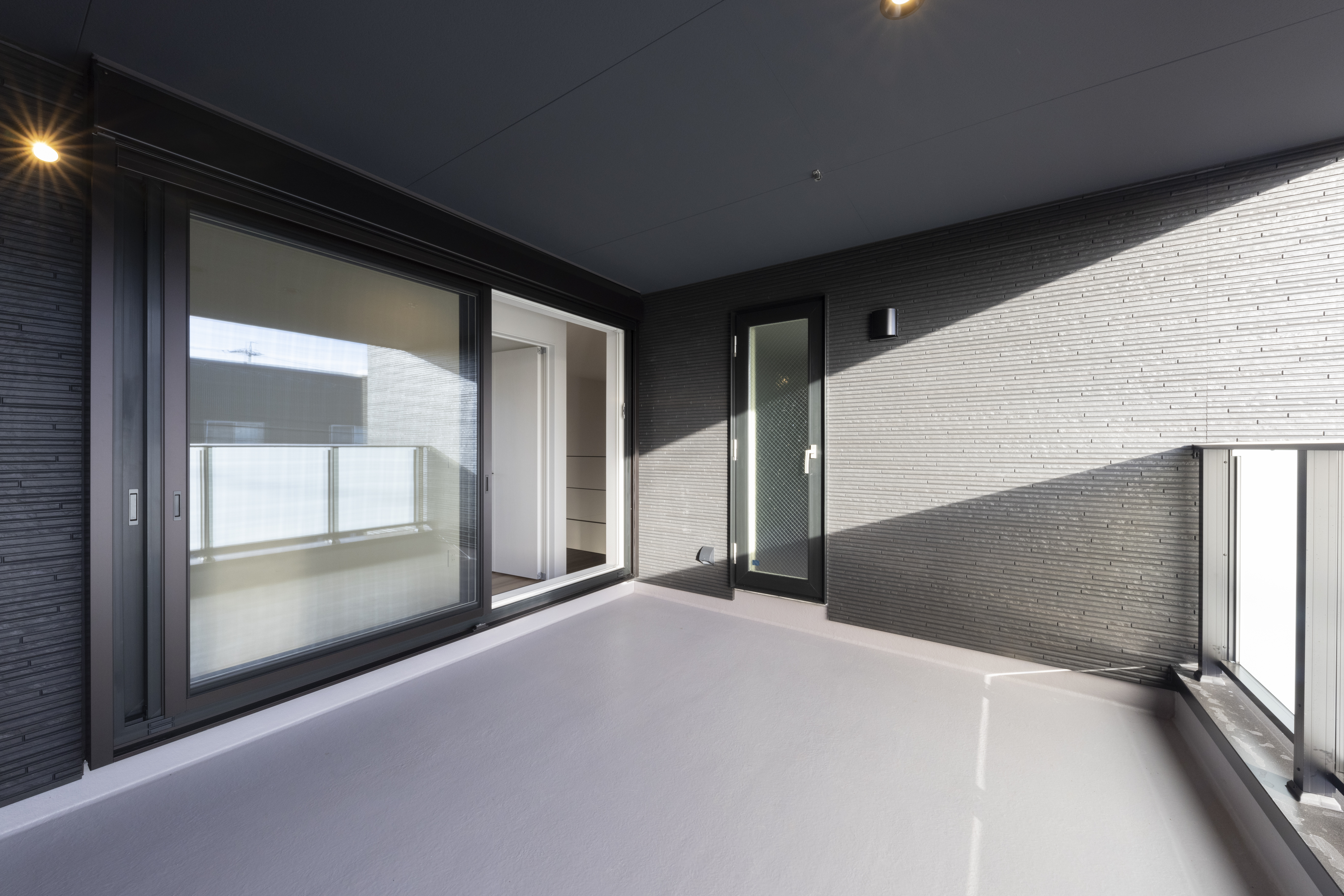 フェスティナ・レンテ｜モダンで広々としたバルコニー。ガラスパネルの手すりが採光をさらに良くし、落ち着いた色合いの壁面が洗練された雰囲気を演出。