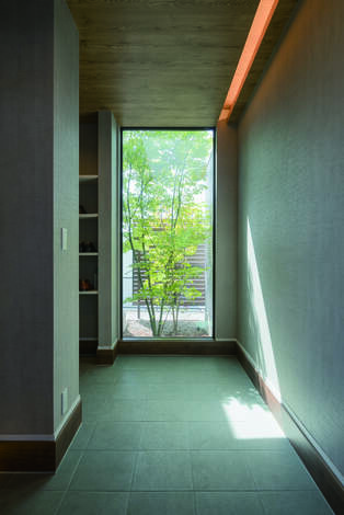 玄関から庭へ抜ける大きなFIX窓。外からの木漏れ日が明るく開放感が広がる
