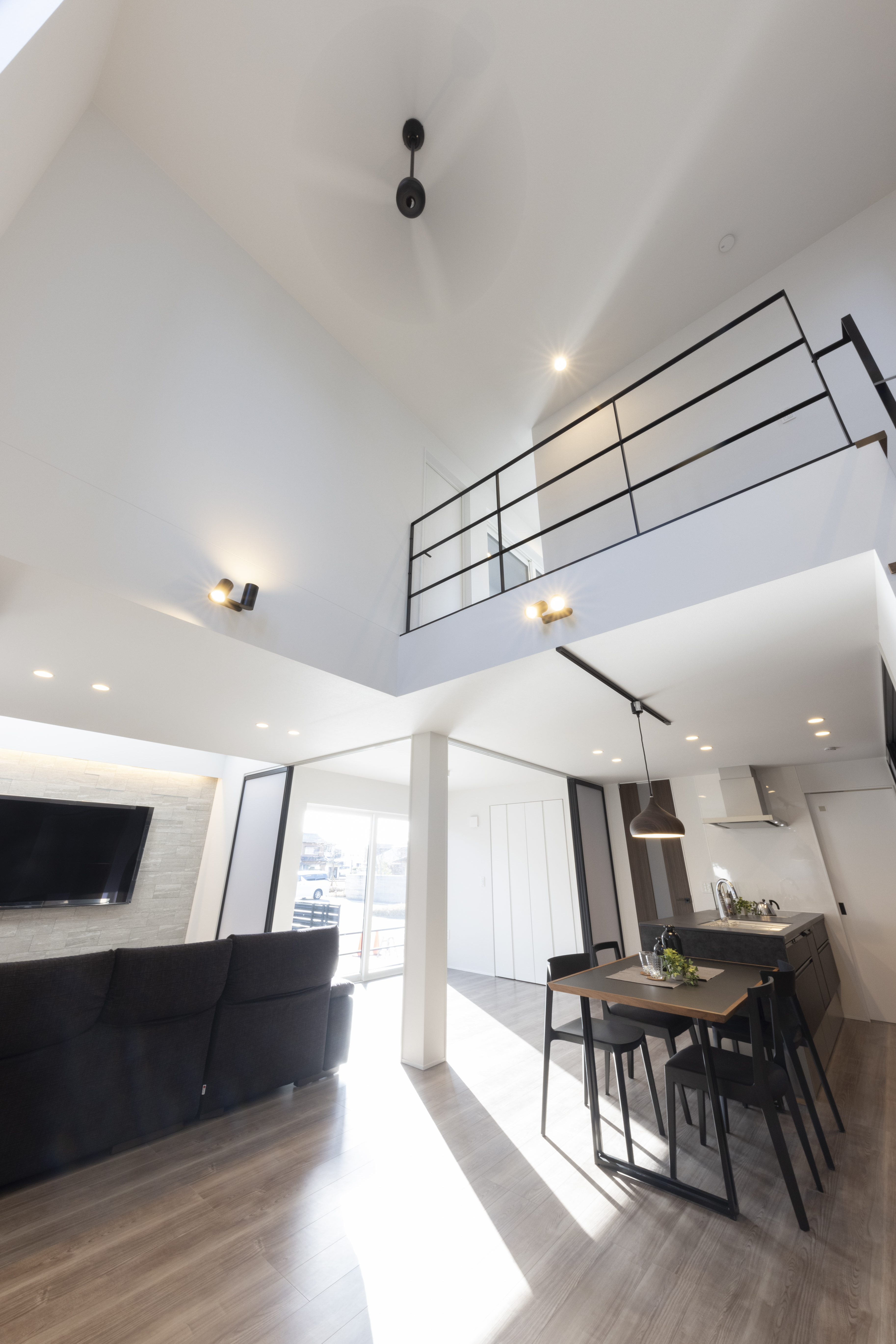 フェスティナ・レンテ｜吹き抜けのある開放的なLDK。モダンなデザインとスタイリッシュな家具が、洗練された空間を演出している。明るい光が差し込む快適なリビングデザイン。