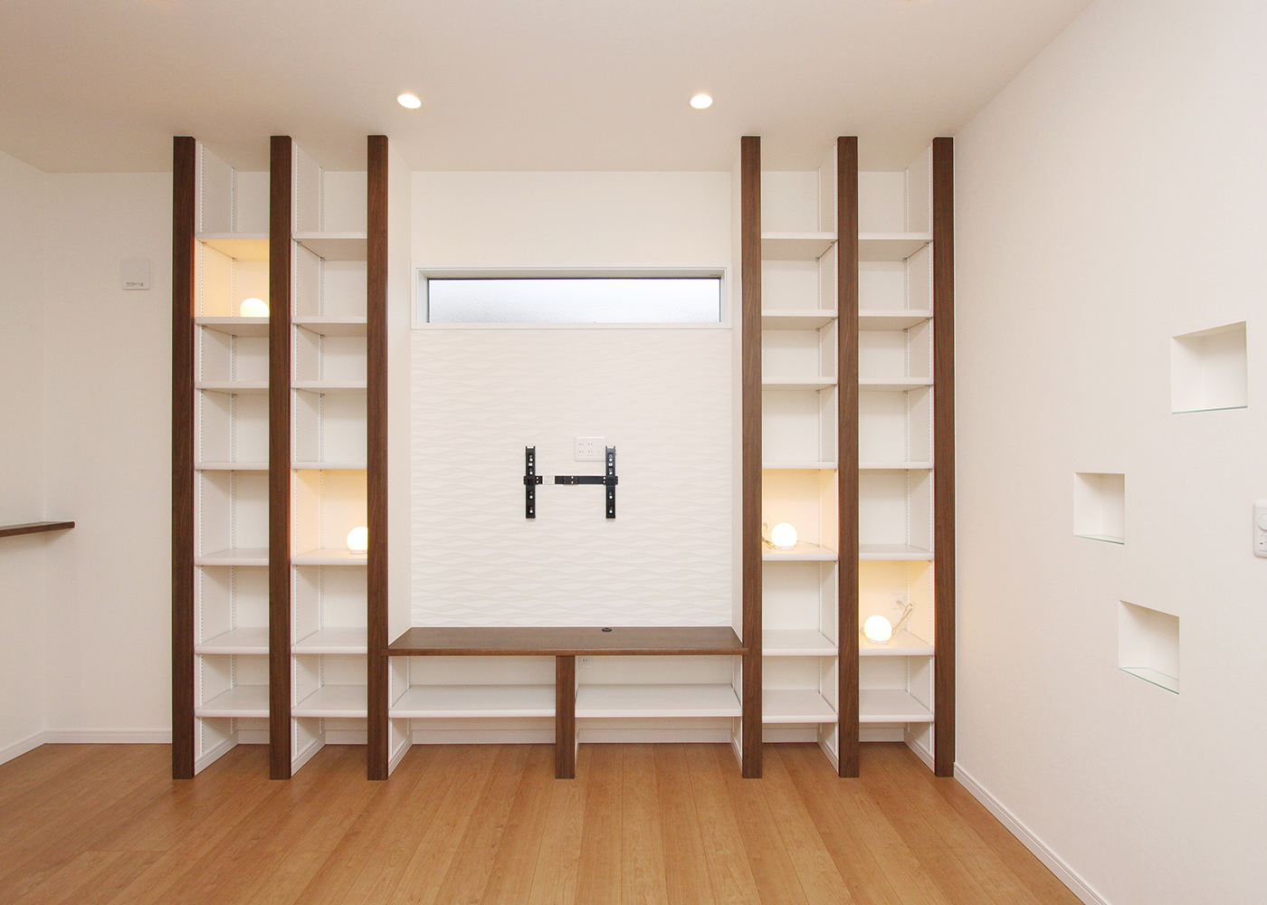 丸昇彦坂建設【デザイン住宅、間取り、インテリア】壁面収納は、収納だけでなく、リビングのデザインの一部としても役割を果たす。さらに、間接照明やニッチの収納部分におしゃれな雑貨を置くことで、変化を楽しめる