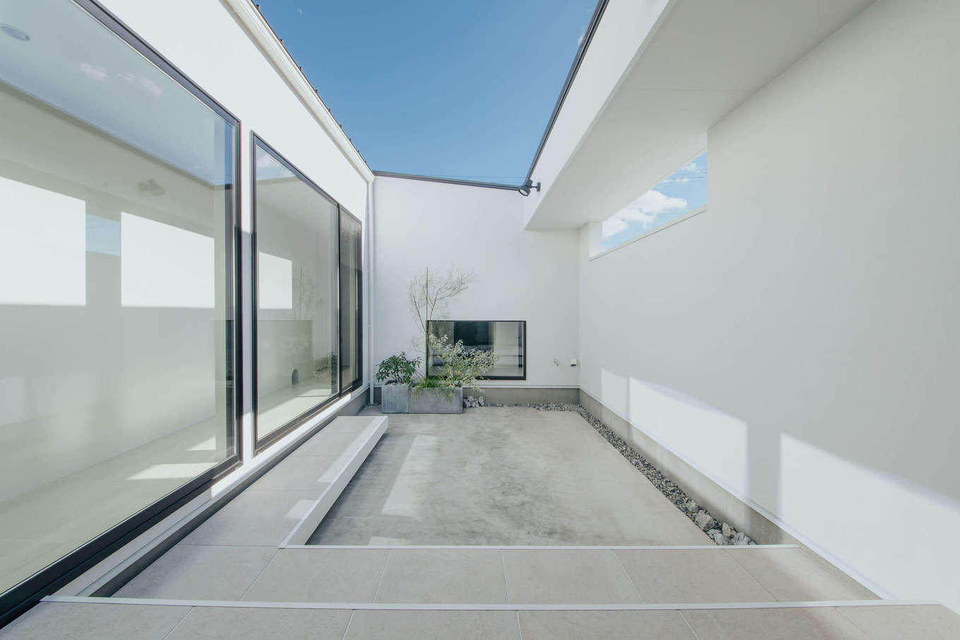 ハウスコネクト【デザイン住宅、ペット、平屋】「猫たちが、家の中でも外の景色や空気を感じられるようにしたい」とオープンエアの中庭を用意。猫が飛び上がっても届かない、なおかつ隣家からも見えない位置を、リビングの窓と同じ大きさに切り取り、光と風の通り道を確保。L字型のタイルデッキは、友達家族とBBQをしたり、猫とまったりくつろいだり、アウトドアリビングとして利用できる