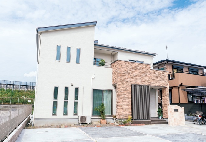 白いサイディングにポーチ周りのレンガが映え、目隠しのためのドアの前のコートラインがアクセントに