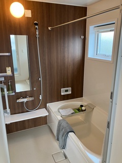 シンプルで落ち着いたデザインのバスルーム。ブラウンのアクセント壁が温かみを添え、清潔感のある空間を演出している。