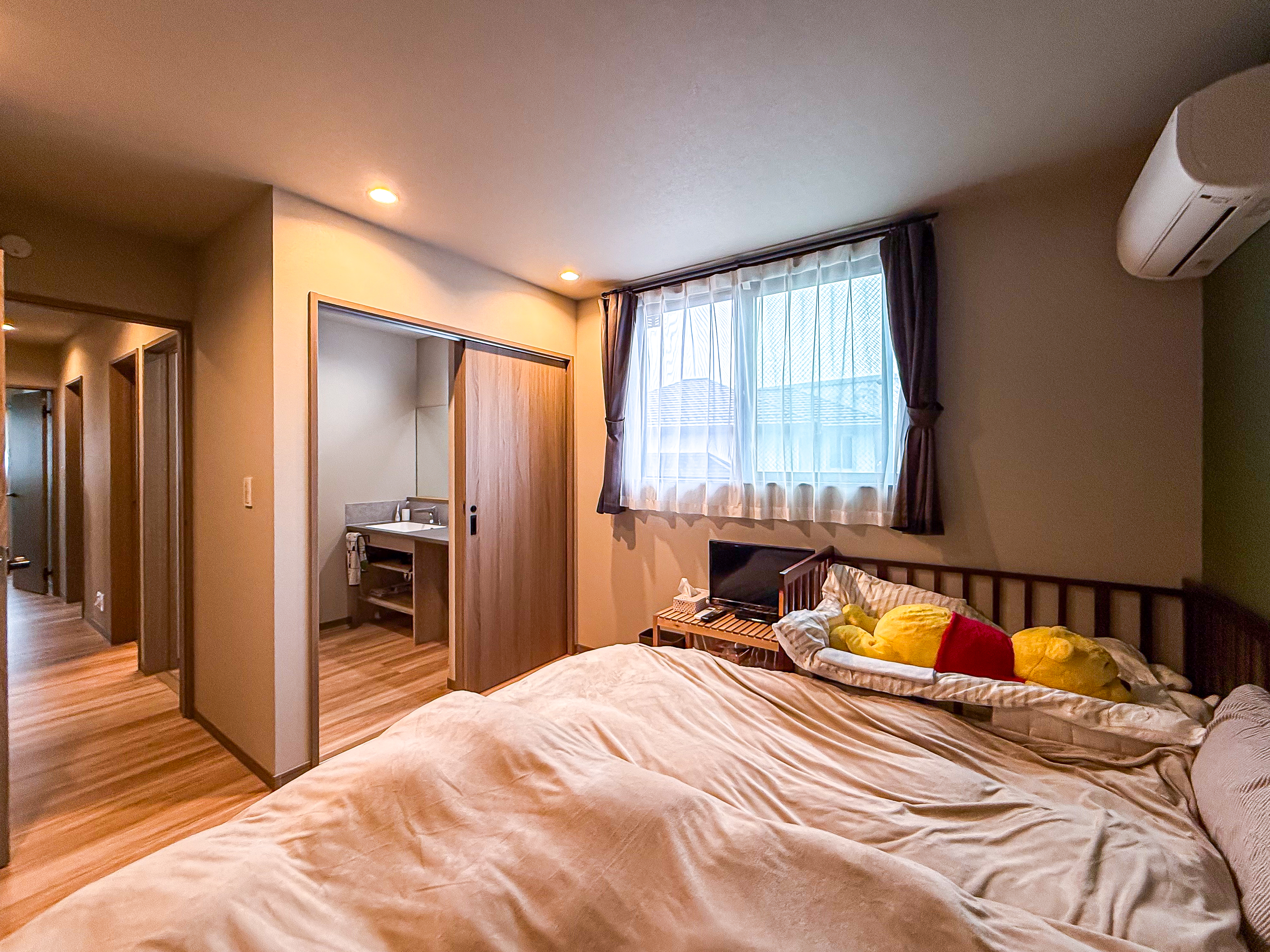 ロイヤルウッド｜ゆったりとしたベッドが置かれた明るい寝室。窓から柔らかな光が差し込み、落ち着いた雰囲気を作り出している。暖かい色調のインテリアが心地よい空間を演出。