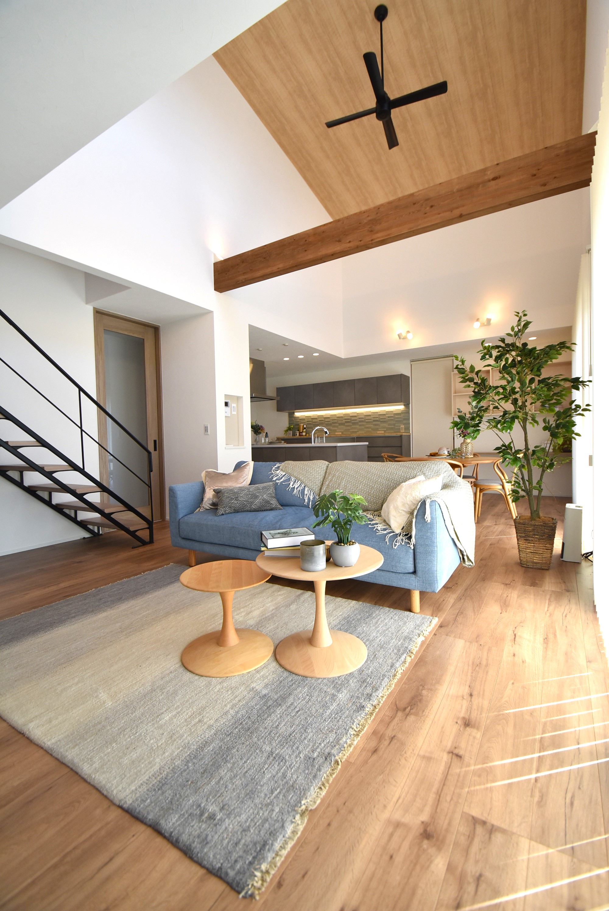 カクニシビルダー｜リビングは、吹き抜けと勾配天井で広々とした空間に仕上がっており、メタルフレームを採用したおしゃれなスケルトン階段が目を惹く。