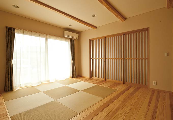 ひらおか建築【和風、二世帯住宅、自然素材】１階のリビングは杉を床材として使い、シックで温かみのある空間に。中央には、2階のリビングと同様に、琉球畳をあしらった