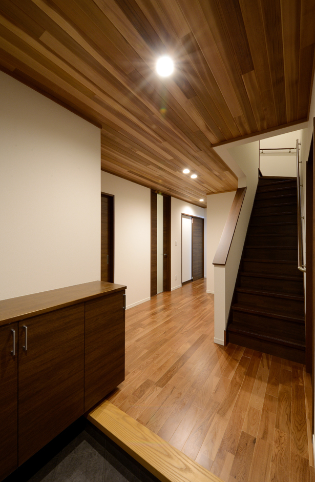 ゆったりとした玄関ホール。ドアを開けた瞬間、木のぬくもりに包まれる。生活サイクルが違うため、1階に親世帯、2階に子世帯を配置。玄関のみ共有で、キッチン、お風呂も別々に