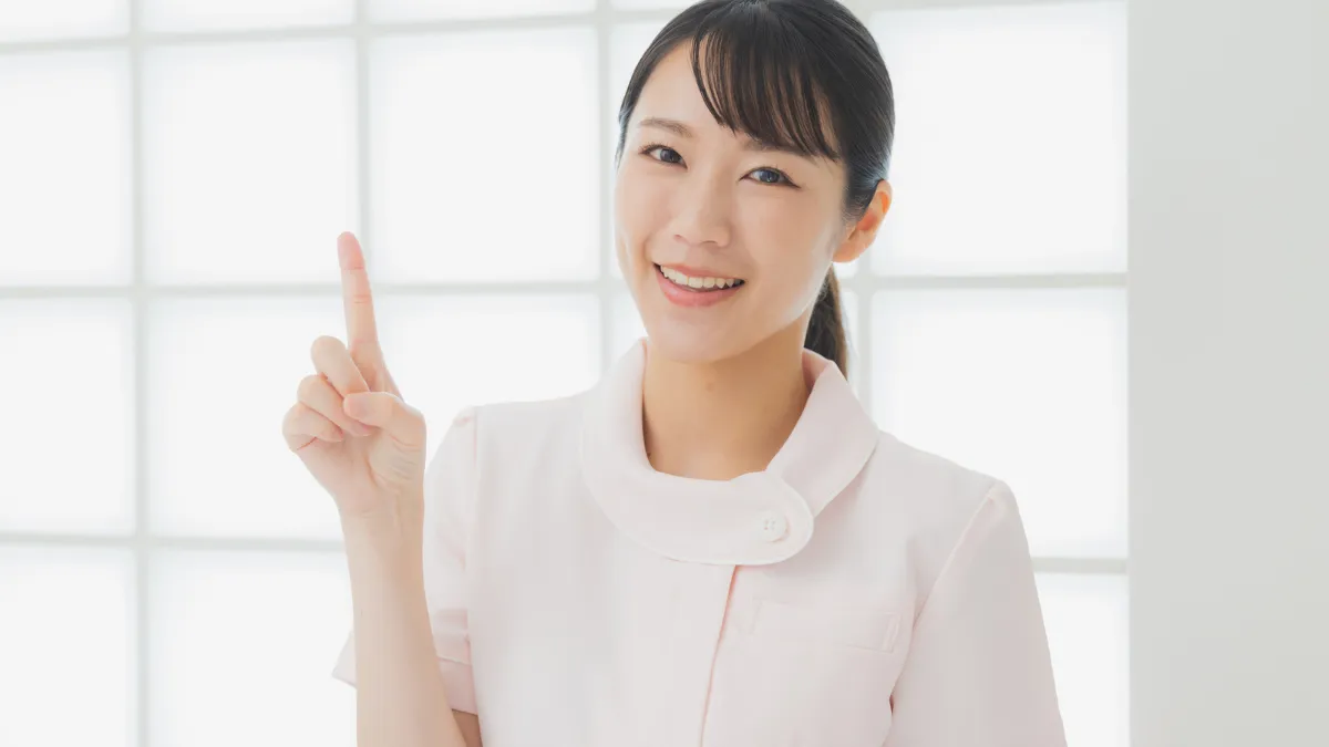 白衣を着た女性が指をさしている