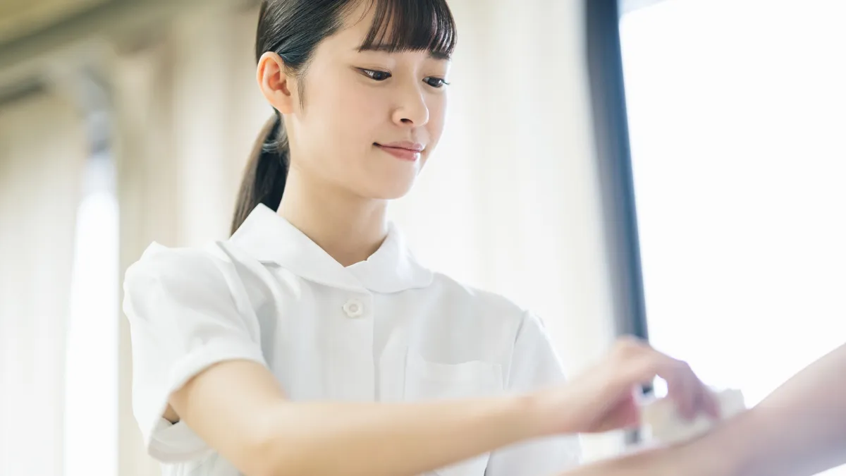 白衣の女性が点滴をしようとしている