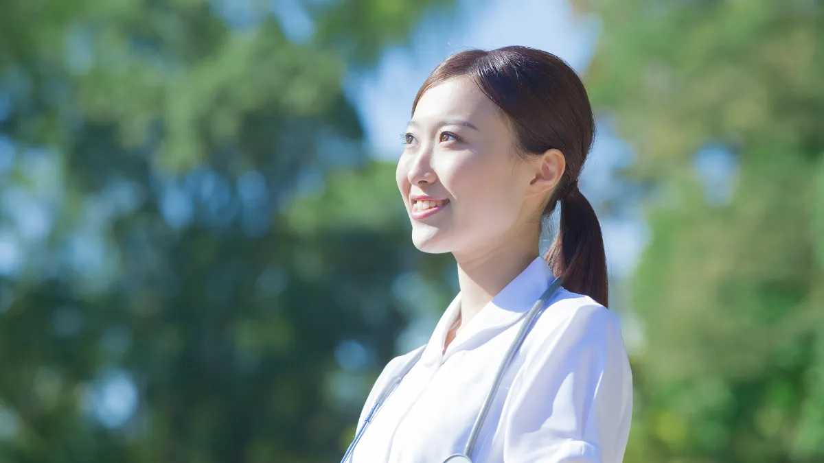 白衣を着た女性が笑顔で前を向いている