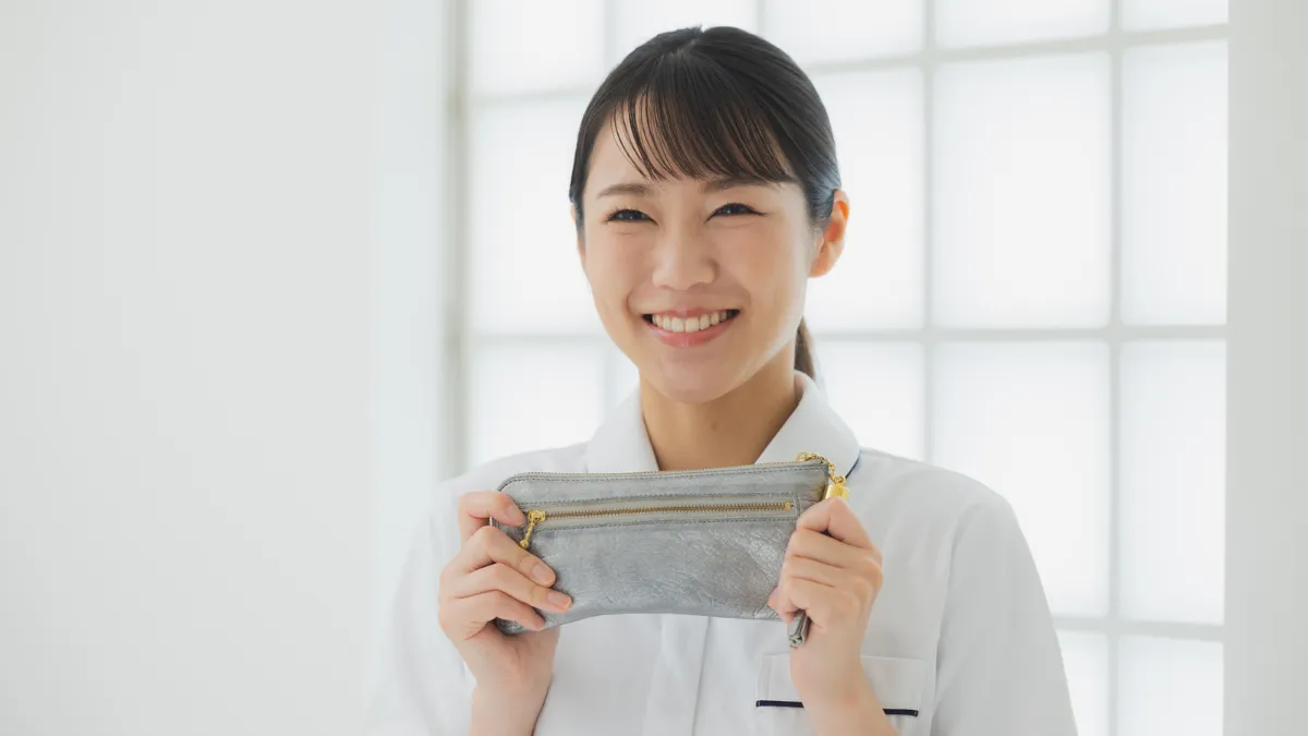 白衣を着た女性が財布を持って笑っている