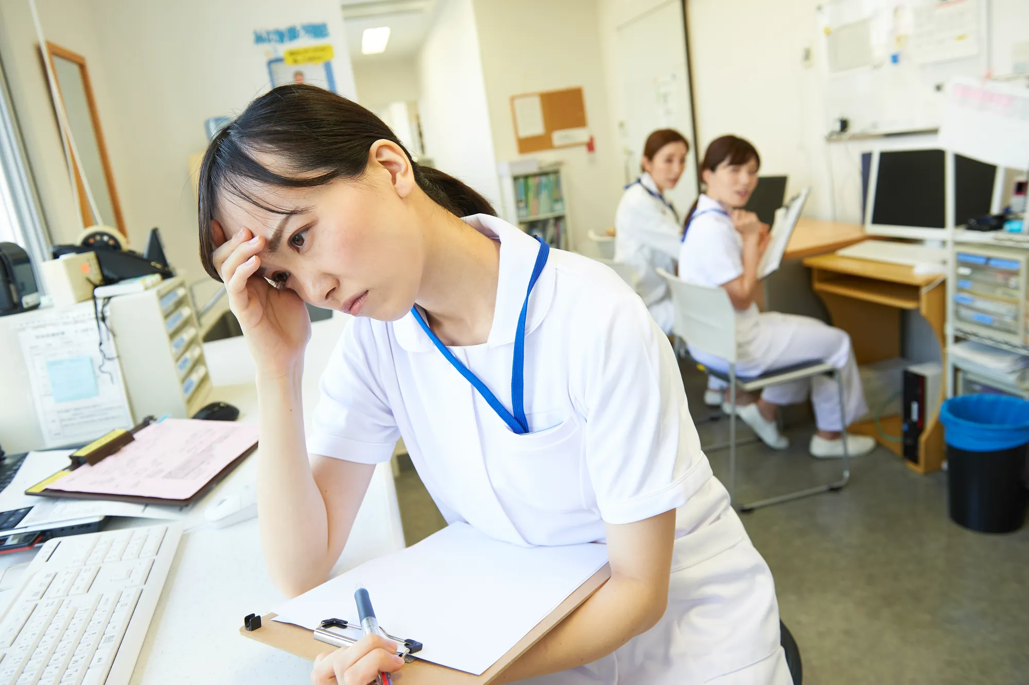 白衣を着た女性が頭を抱えてる