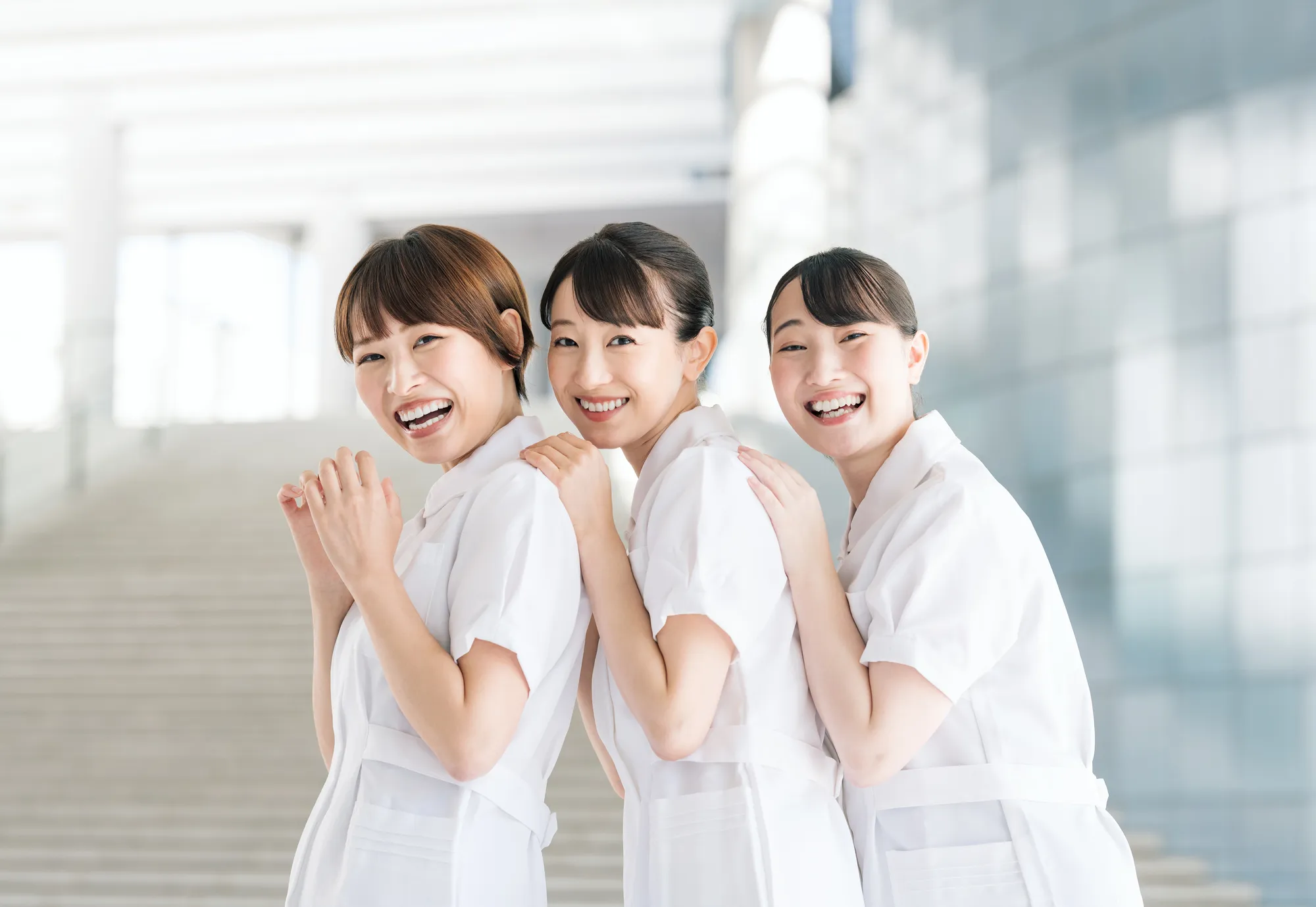 白衣を着た女性3人が重なって笑顔でこちらを向いている