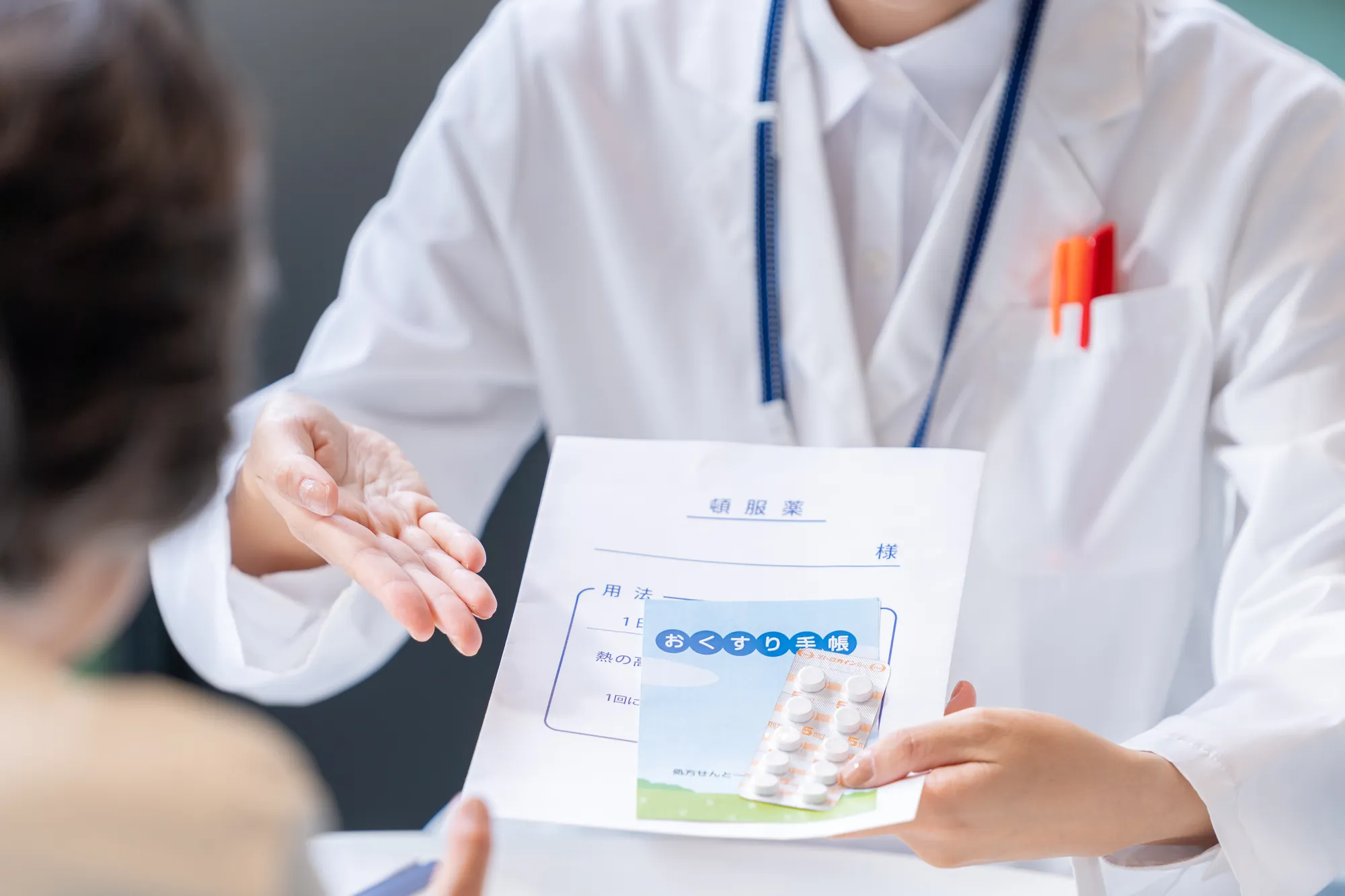 白衣を着た人が薬袋をもっている