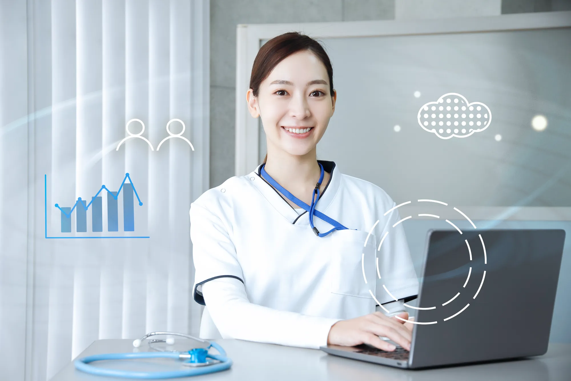 白衣を着た女性がパソコンの前で笑顔でこちらを向いている