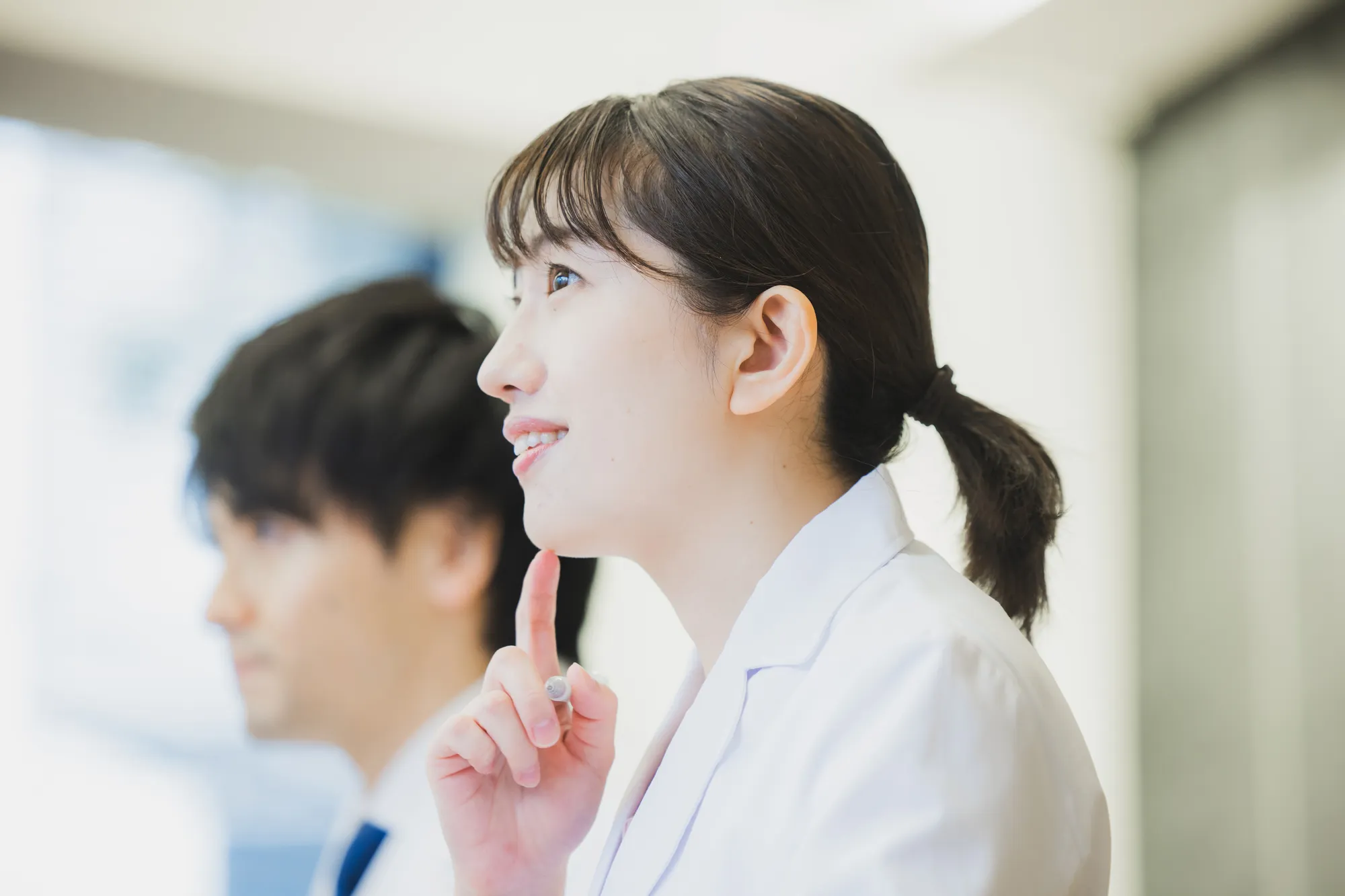 白衣を着た方がペンを持って誰かの話を聞いている