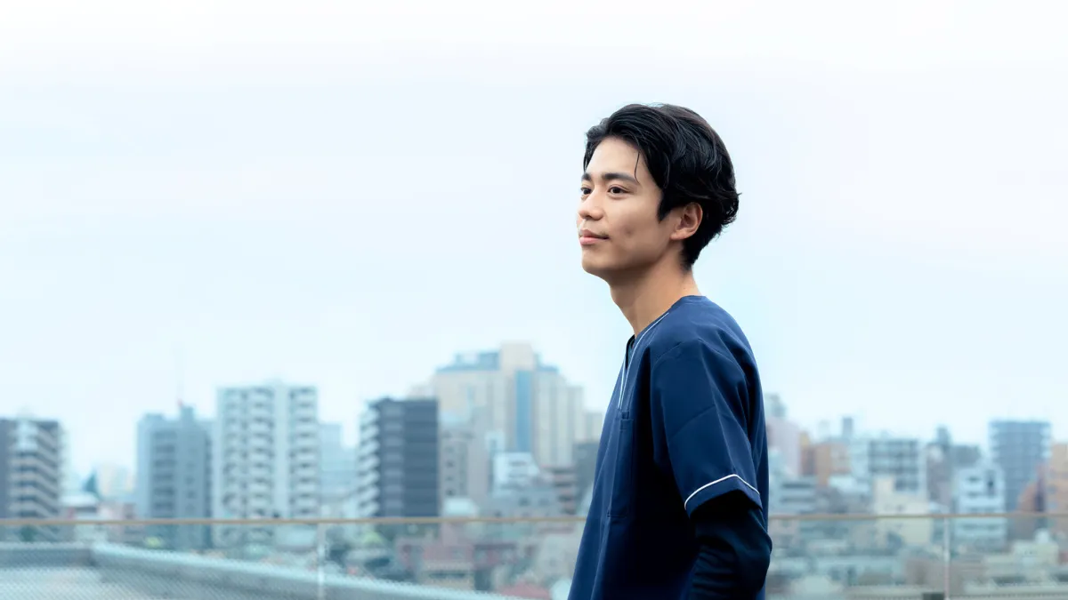 都会のビルの屋上に立つ男性医療従事者