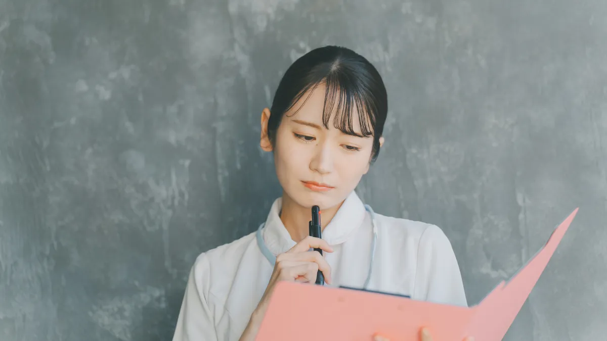 白衣を着た女性がバンをもって悩んでる