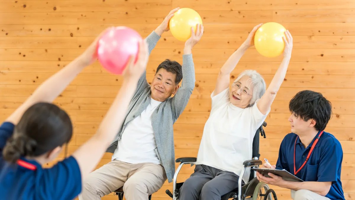 高齢者と機能訓練指導員がボールを使って体操をしている様子