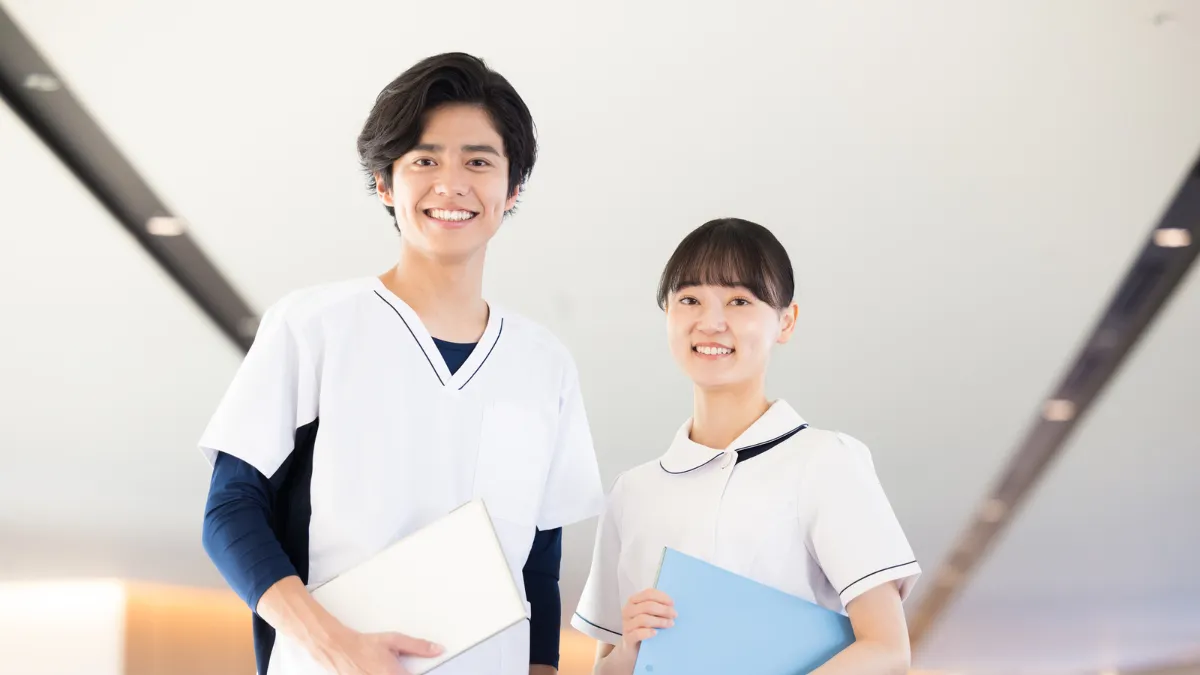 白衣を着た男女が笑顔で立っている