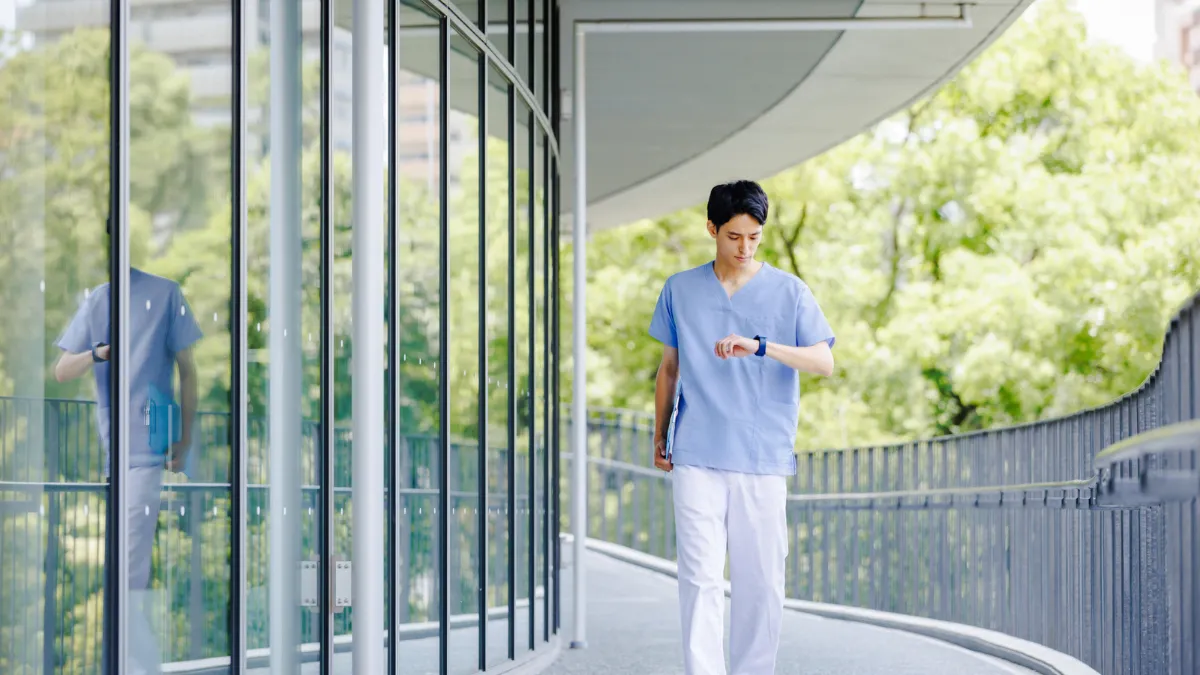 白衣を着た男性が腕時計を見ながら走っている