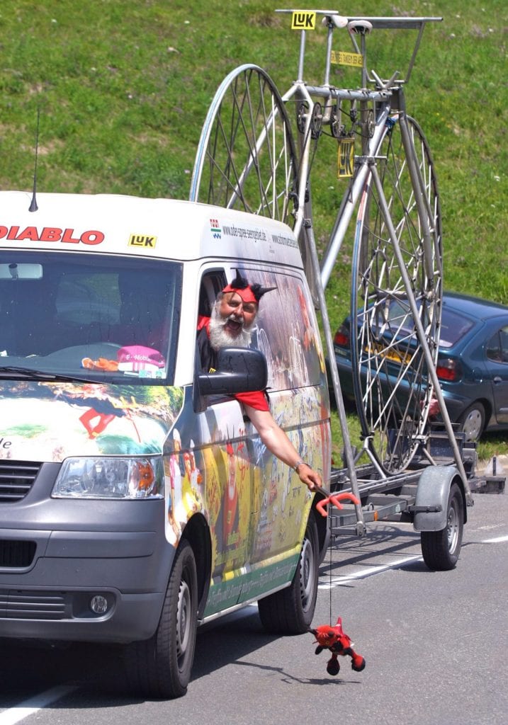 悪魔おじさんのクルマは、大きな自転車のモニュメントを牽引している ©Takashi NAKAZAWA