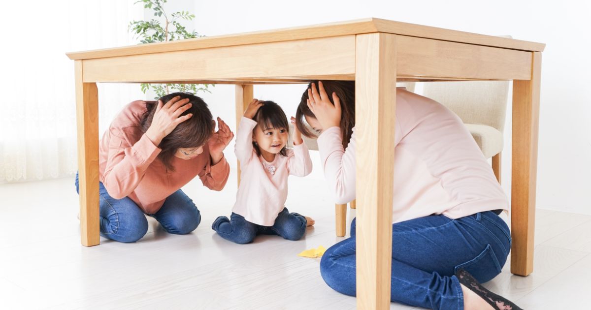 机の下に隠れる女の子と女性2人