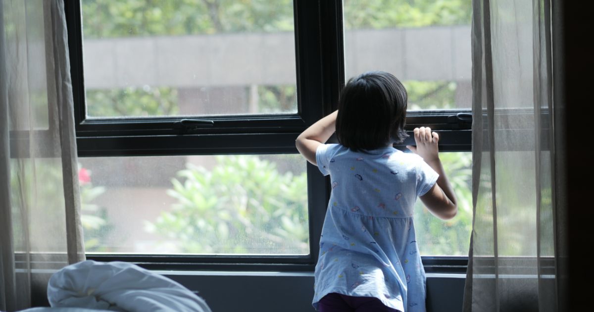窓の外を眺める子どもの後ろ姿