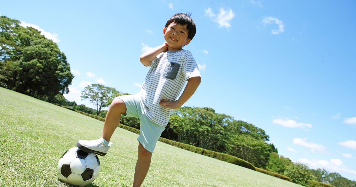 晴れた日にサッカーボールに足をかける少年