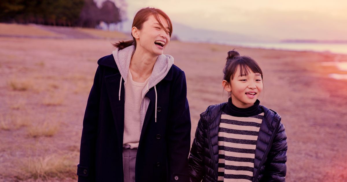 冬の海辺を歩く母娘