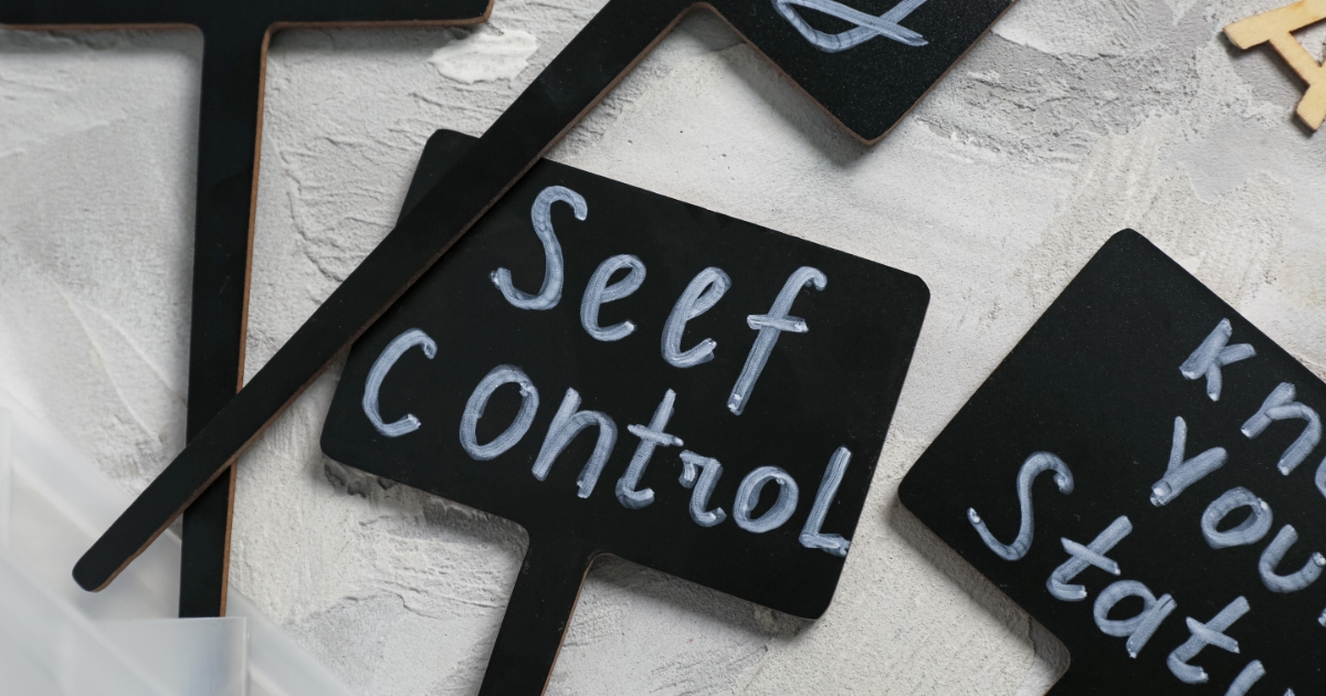 チョークで「Self Control」と手書きされた黒いプレートが、白い背景の上に並べられている